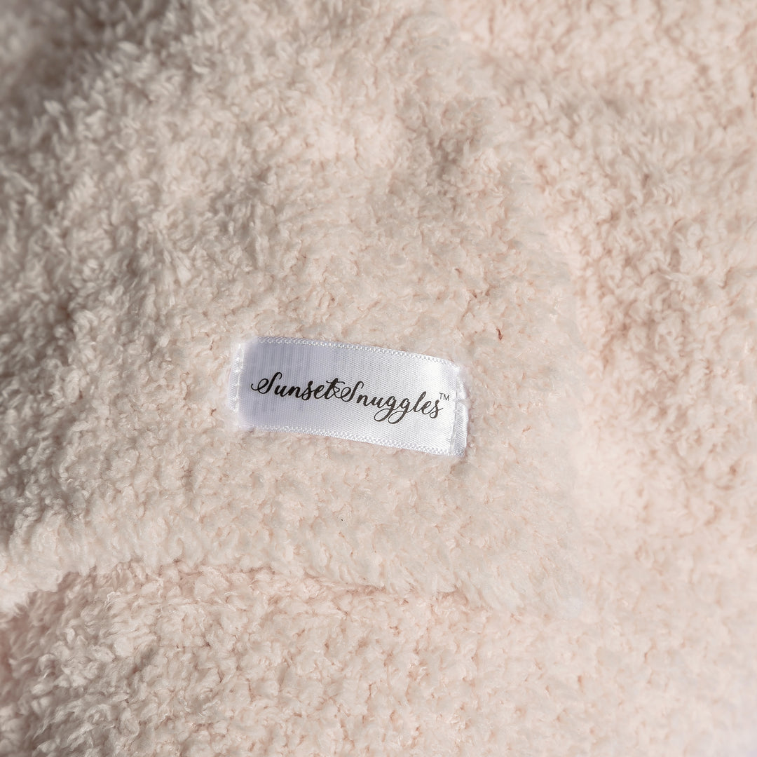 Close-up of a textured fabric surface with a 'Sunset Snuggles' label.