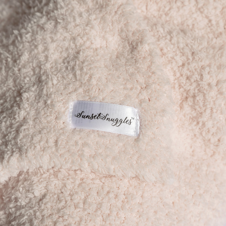 Close-up of a textured fabric surface with a 'Sunset Snuggles' label.