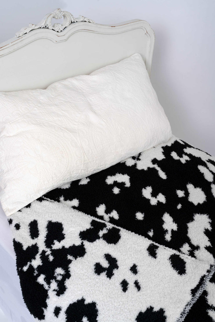 cow print black and white twin blanket on a bed