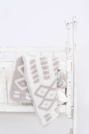diamond point beige and white lovey baby blanket on a cradle