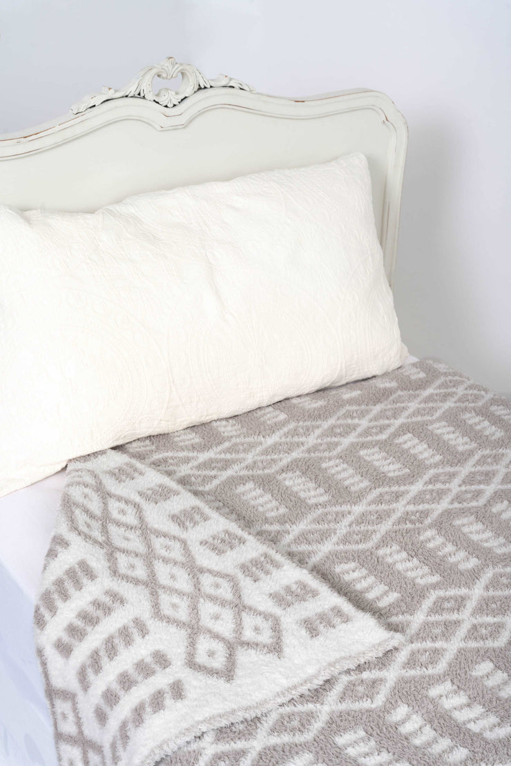 diamond point beige and white extended throw blanket on a twin bed
