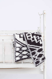 diamond tile shale and white lovey baby blanket on a crib