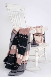 world's softest fluffy throw blanket in pink cream grey and black with geometric stripes on rocking chair