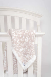 leopard print blushing beige and white toddler blanket on a crib