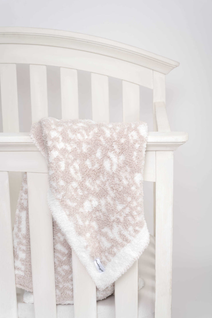 leopard print blushing beige and white toddler blanket on a crib