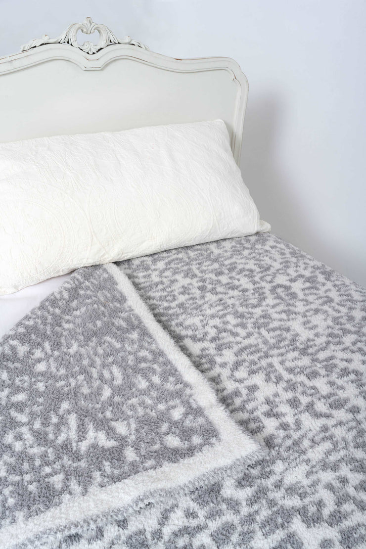 leopard print ultimate grey and white extended throw blanket on a bed