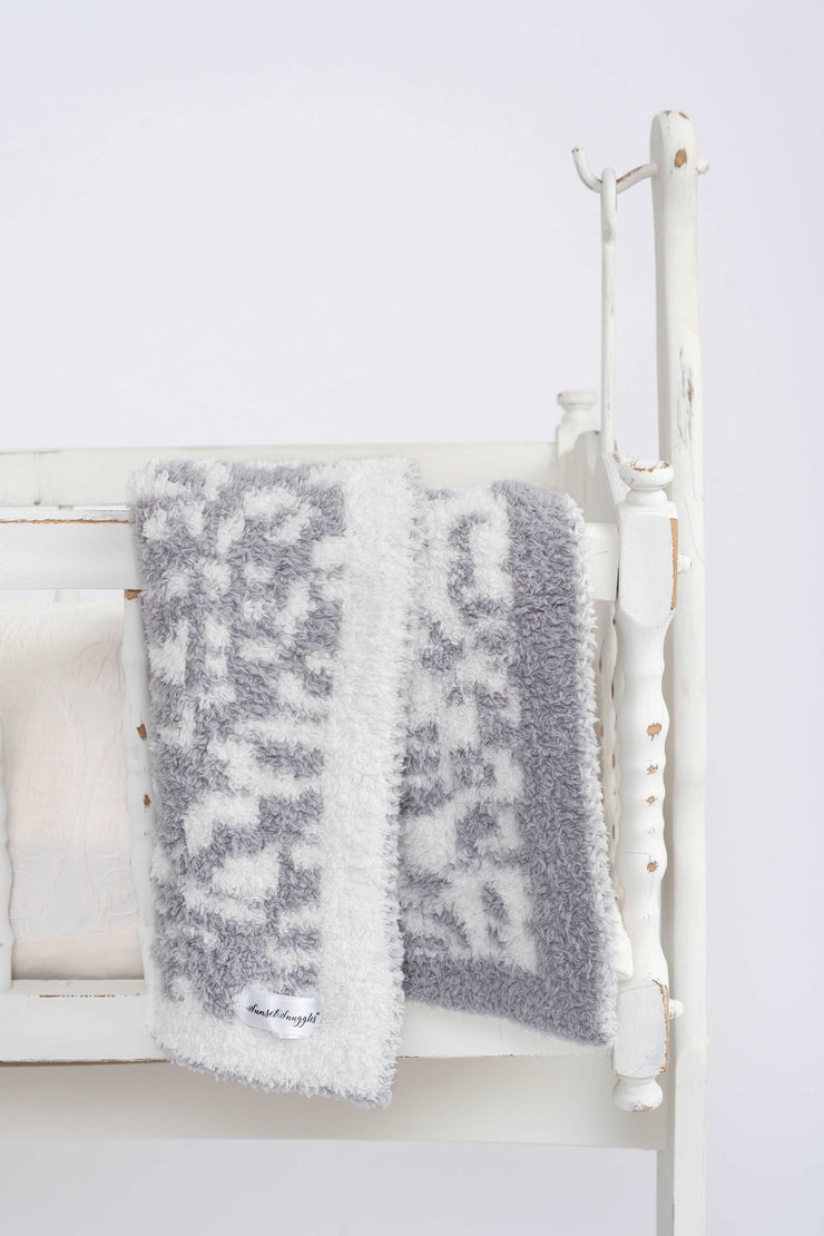 leopard ultimate grey and white toddler baby blanket on a cradle
